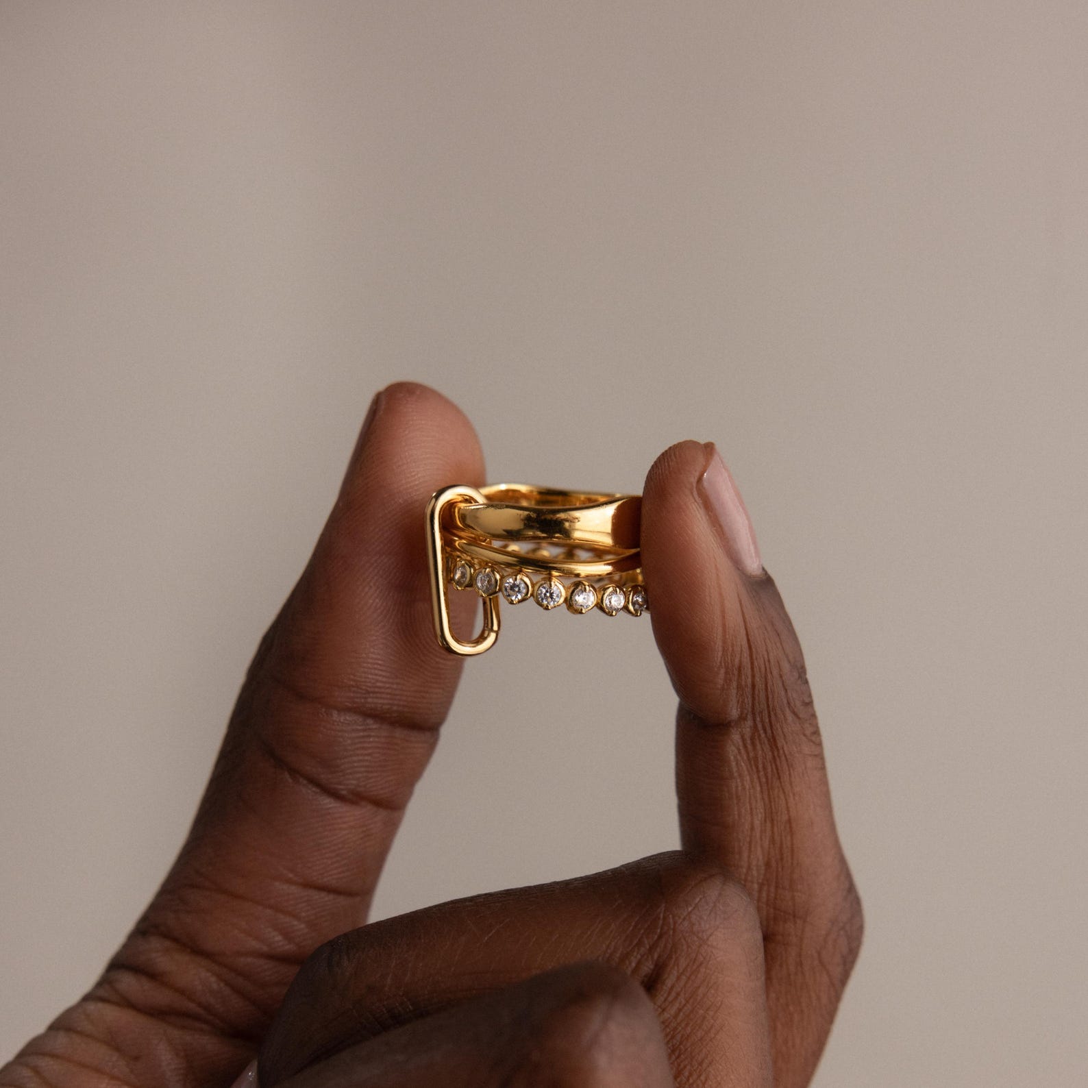 Hand holding the Multipurpose Mixed Metal Clasp Set featuring a unique dangling detail, perfect for stylish stacking, against a neutral background.