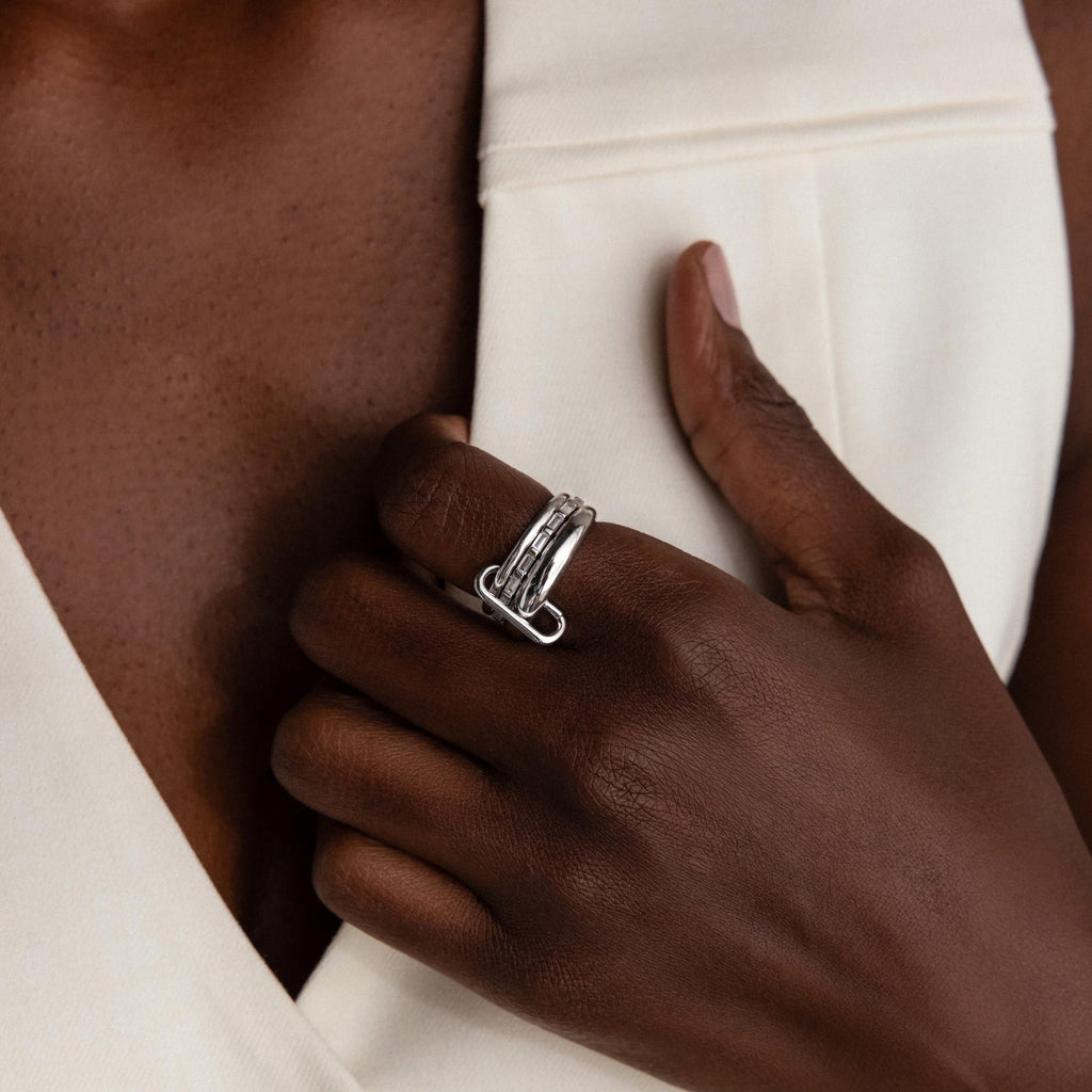 A hand with a Multipurpose Mixed Metal Clasp Set, ideal for stacking, rests on the chest against a white sleeveless garment.