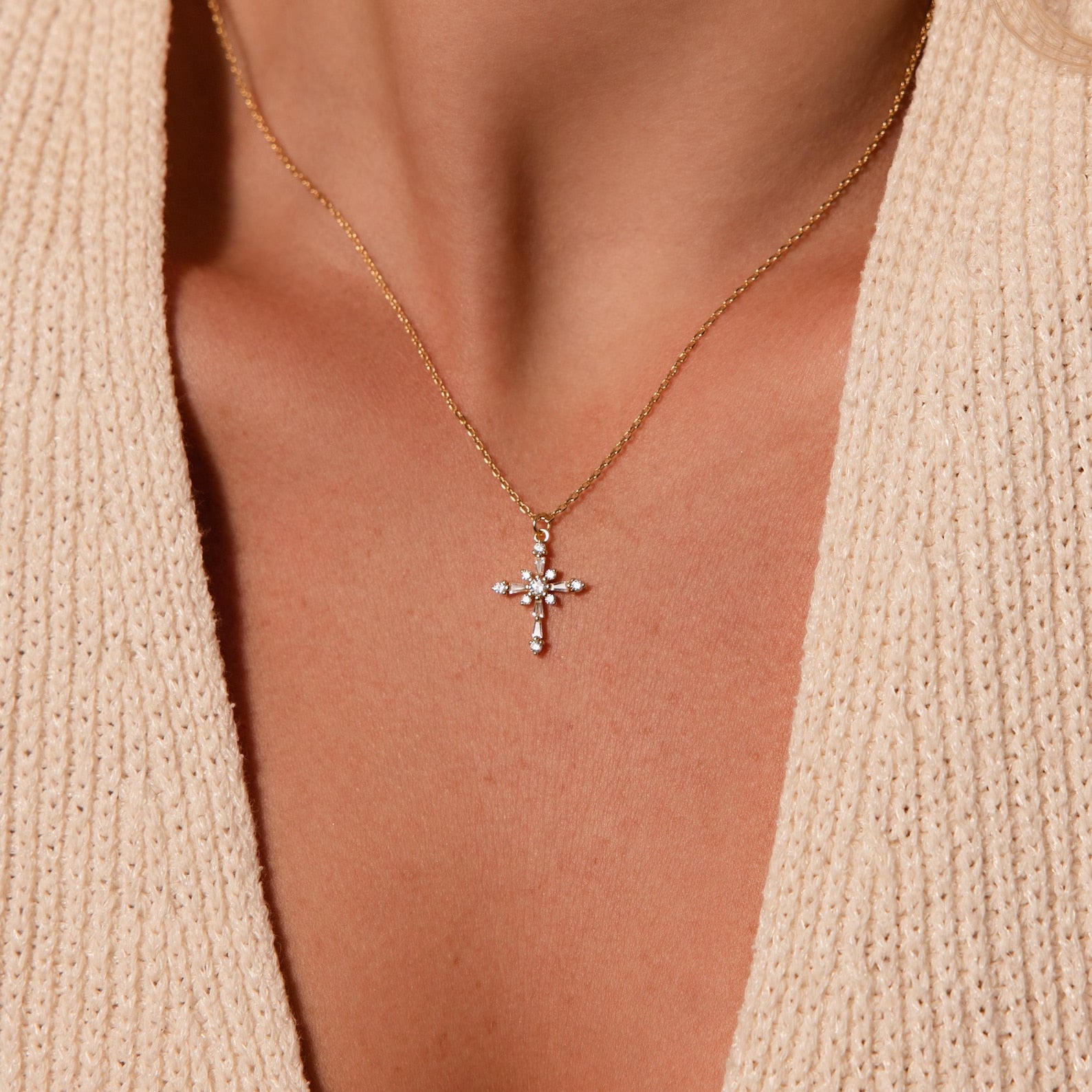 The Vintage Diamond Cross Necklace features a sparkling pendant that shines beautifully over a beige knit top.