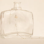 The Baroque Pearl Station Necklace in Sterling Silver is elegantly displayed on a clear glass bottle against a neutral background, making it the perfect wedding jewelry.