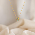 Interlocking Birthstone Necklace displayed on soft cream fabric—an elegant keepsake jewelry piece with a circular, turquoise-studded pendant, making it a thoughtful gift for mom.