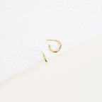 Gold stud hoop earrings on a textured white background