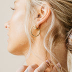 A close-up of a blonde woman wearing the Dainty Opal Earrings Set, her hand gently resting on her neck.