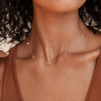 A woman in a brown top showcases modern elegance with the Diamond Station Necklace, featuring delicate beads for a refined look.