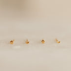 The Tiny Moon & Star Studs set includes two gold star studs and two crescent moon studs, creating a dreamy constellation-inspired look—perfect for lovers of dainty jewelry. Presented on a soft, neutral background.