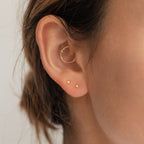 Close-up of a woman's ear wearing the Tiny Moon & Star Studs in her lobe and a small hoop in her cartilage—perfect constellation-inspired jewelry for celestial style lovers.