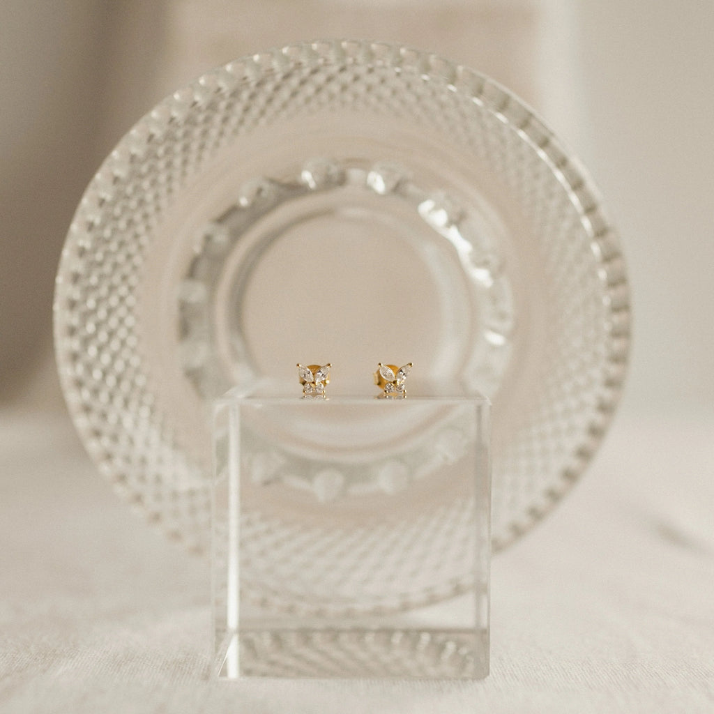 Diamond Butterfly Earrings Set displayed on a clear block with a textured glass plate in the background—ideal for layering or pairing for an elegant style.