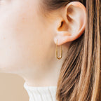 Close-up of an ear with light skin and brown hair wearing a gold Safety Pin Earrings Set in a minimalist U-shape.