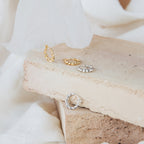 Naomi Twisted Hoops in Sterling Silver, shown on beige bricks with a soft fabric background, bring elegant style to any outfit.