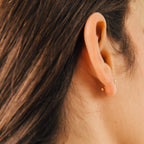 Close-up of a person's ear with brown hair, wearing Nora Duo Studs in 18K Gold—timeless ball stud earrings for everyday style.