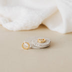 The Meg Huggies in 18K Gold are displayed on round speckled stones, set against a backdrop of soft white fabric.