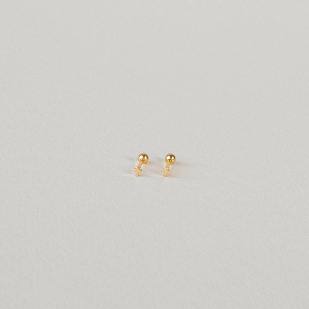 The Tiny Cross Studs are delicate stud earrings with small gold cross charms, shown against a plain white background.