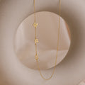 The Sideways Initial Necklace is shown with dangling letters spelling MRS on a round, beige abstract background—a unique and thoughtful Christmas gift.