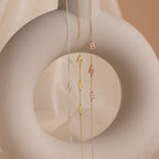 The Sideways Initial Necklace, featuring three delicate chain necklaces with letter charms, drapes elegantly on a light beige ceramic sculpture—making it a thoughtful and unique Christmas gift.