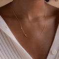 A person in a white ribbed button-up top wears the Sideways Initial Heart Necklace, featuring a gold A and heart pendant.