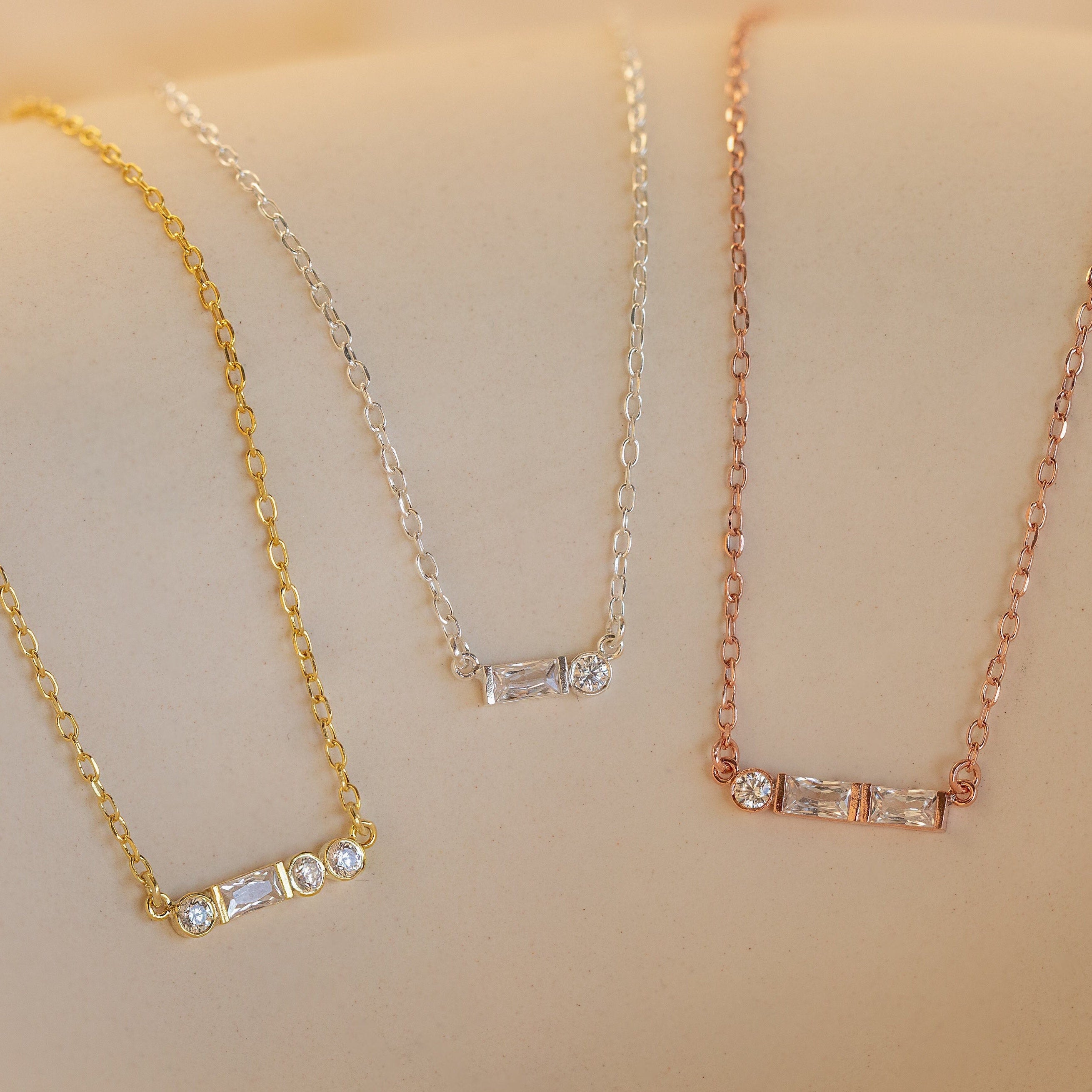 The Initial Morse Code Necklace features three bar necklaces in gold, silver, and rose gold with clear gemstones, offering a refined look inspired by Morse code—perfect for fans of personalized jewelry.