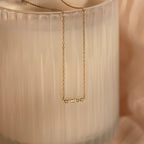 Initial Morse Code Necklace in gold, featuring delicate links, displayed on a textured frosted glass background.