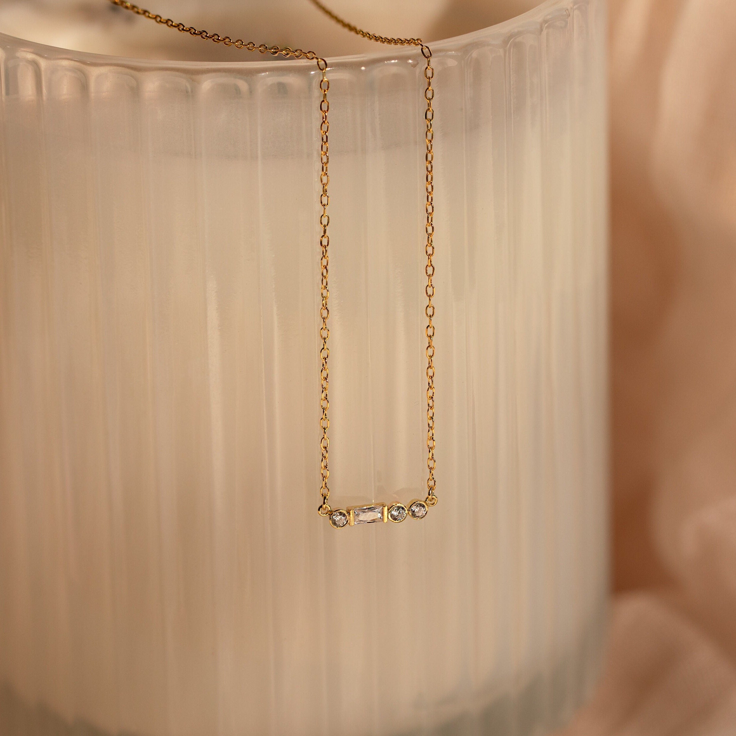 Initial Morse Code Necklace in gold, featuring delicate links, displayed on a textured frosted glass background.