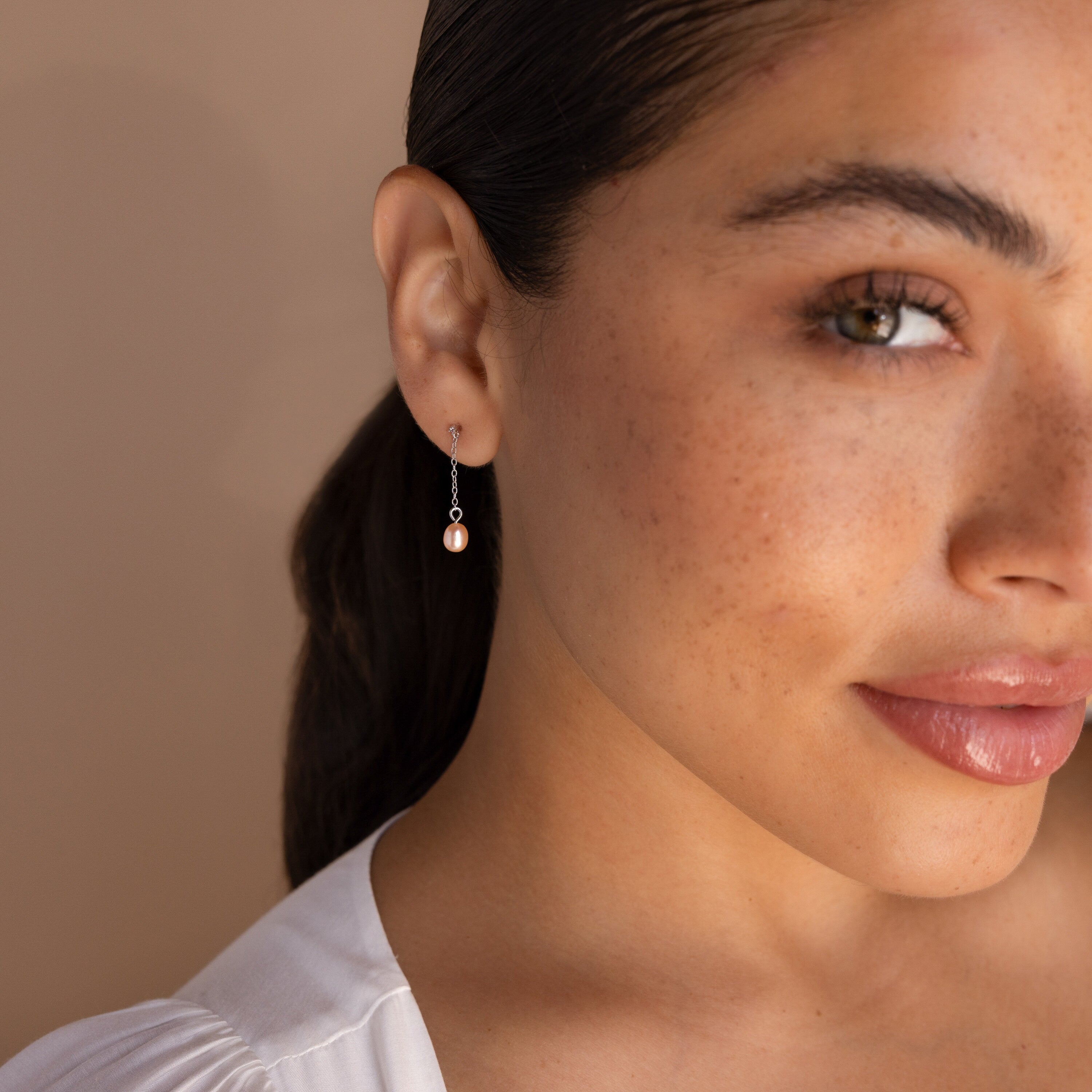 A close-up of a woman's face, highlighting the Isha Pink Pearl Earrings that add a touch of sophistication to her look.