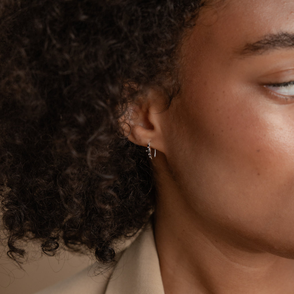 A close-up of a woman's face, highlighting her modern Amaya Black Marquise Threaders from the latest jewelry collection.
