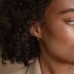 A close-up of a woman's face, highlighting her modern Amaya Black Marquise Threaders from the latest jewelry collection.