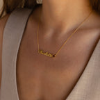 The Mellow Name Heart Birthstone Necklace featuring "Charlotte" sits elegantly on a woman's neck, beautifully complementing her beige v-neck top—a perfect choice for Minimalist Jewelry enthusiasts.