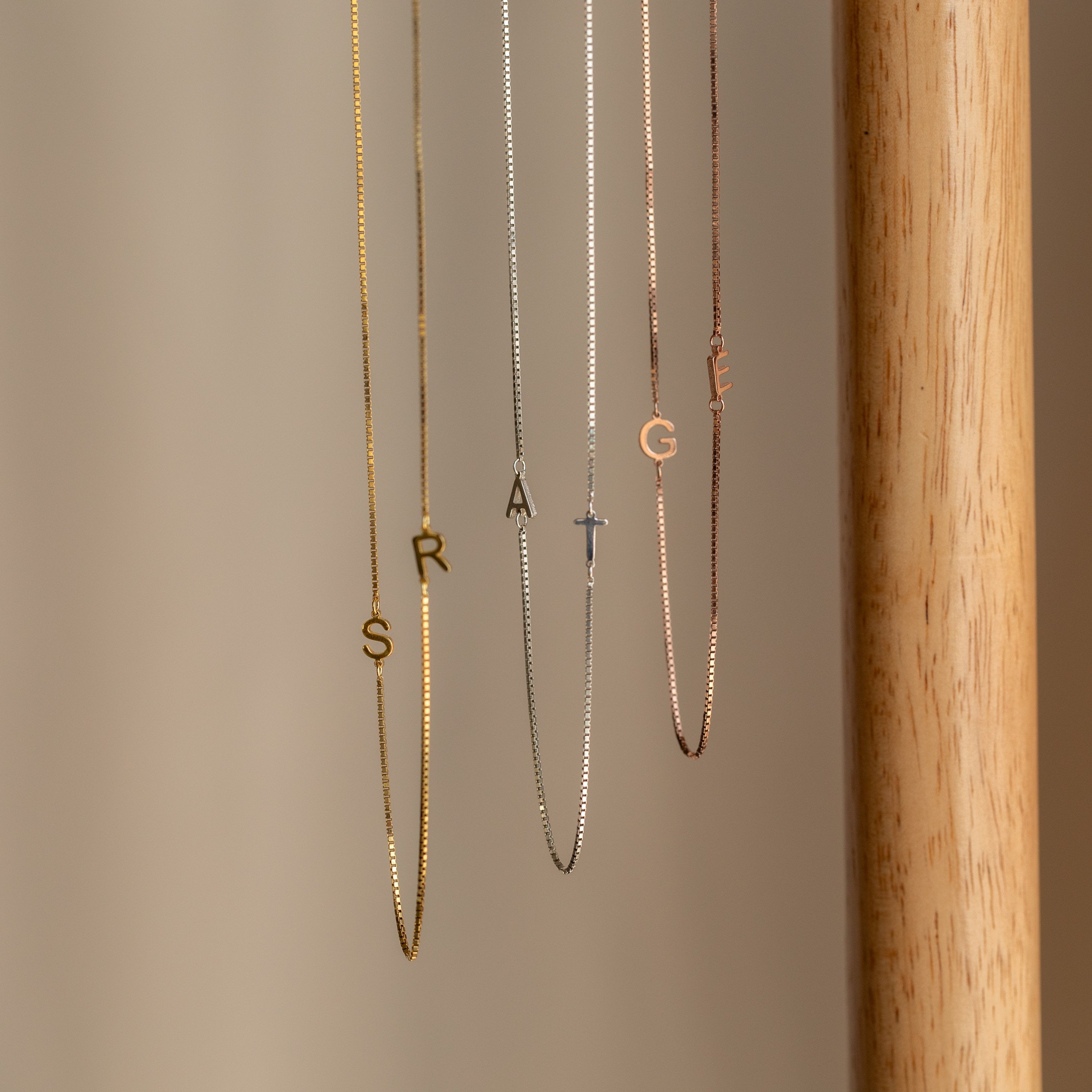 Two Duo Initial Necklaces in Box Chain display personalized letter charms spelling STRANGE, set against a neutral background.