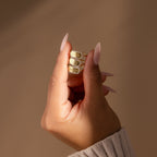 A hand with long nails displays three gold stacking rings, including a personalized minimalist Custom Pave Hexagon Ring, all stacked on one finger against a neutral background.
