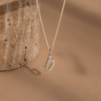 The Gothic Pave Initial Necklace features a diamond-encrusted “S” pendant on a gold chain, displayed against a neutral brown background—offering elegant, personalized style to any outfit.