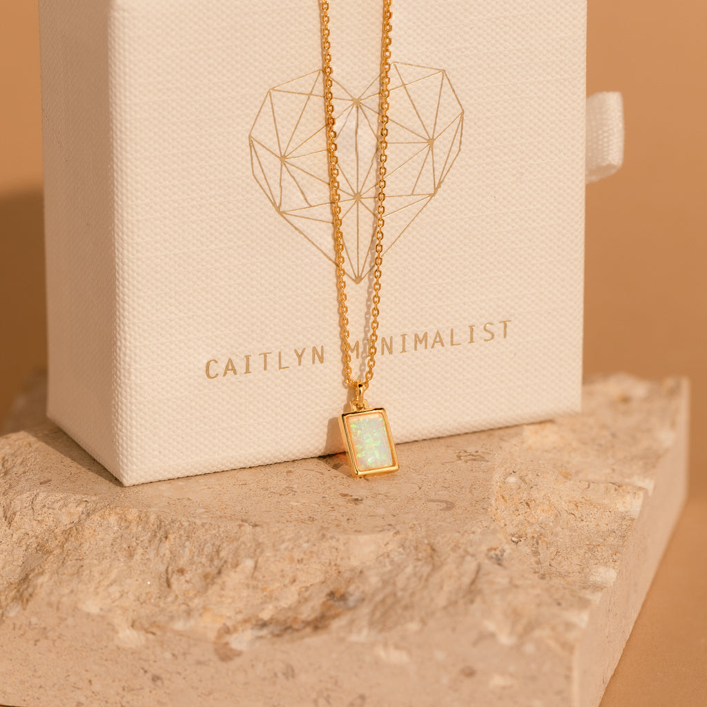 The White Opal Rectangle Necklace showcases a rectangular opal pendant on a gold chain—ideal for bridal jewelry or adding elegance to your everyday style.