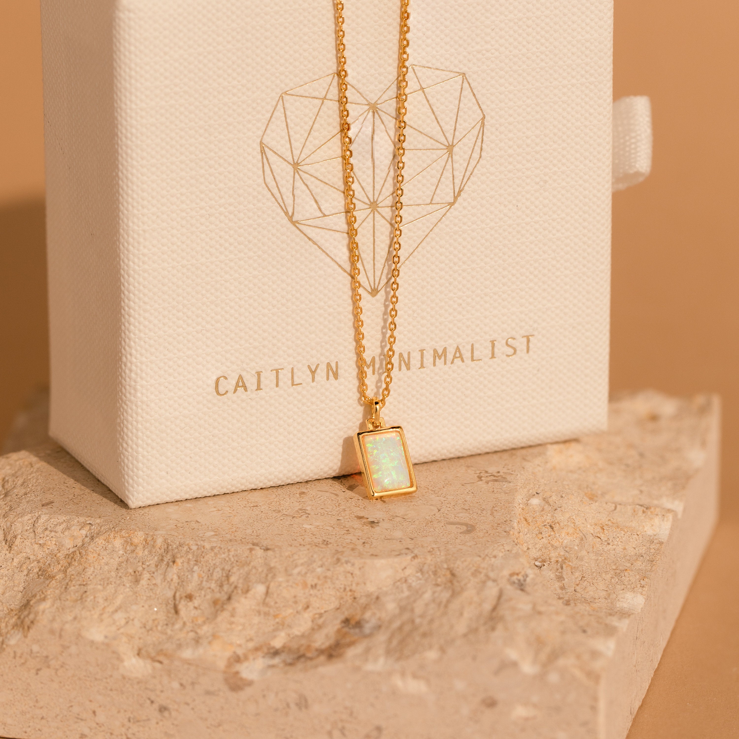 The White Opal Rectangle Necklace showcases a rectangular opal pendant on a gold chain—ideal for bridal jewelry or adding elegance to your everyday style.