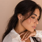 A woman with her hand on her neck, showcasing elegant White Opal Inlay Hoops.