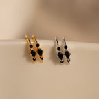 Amaya Black Marquise Threaders—gold and silver modern earrings with black stones, displayed on a smooth cream surface—make an elegant addition to any jewelry collection.