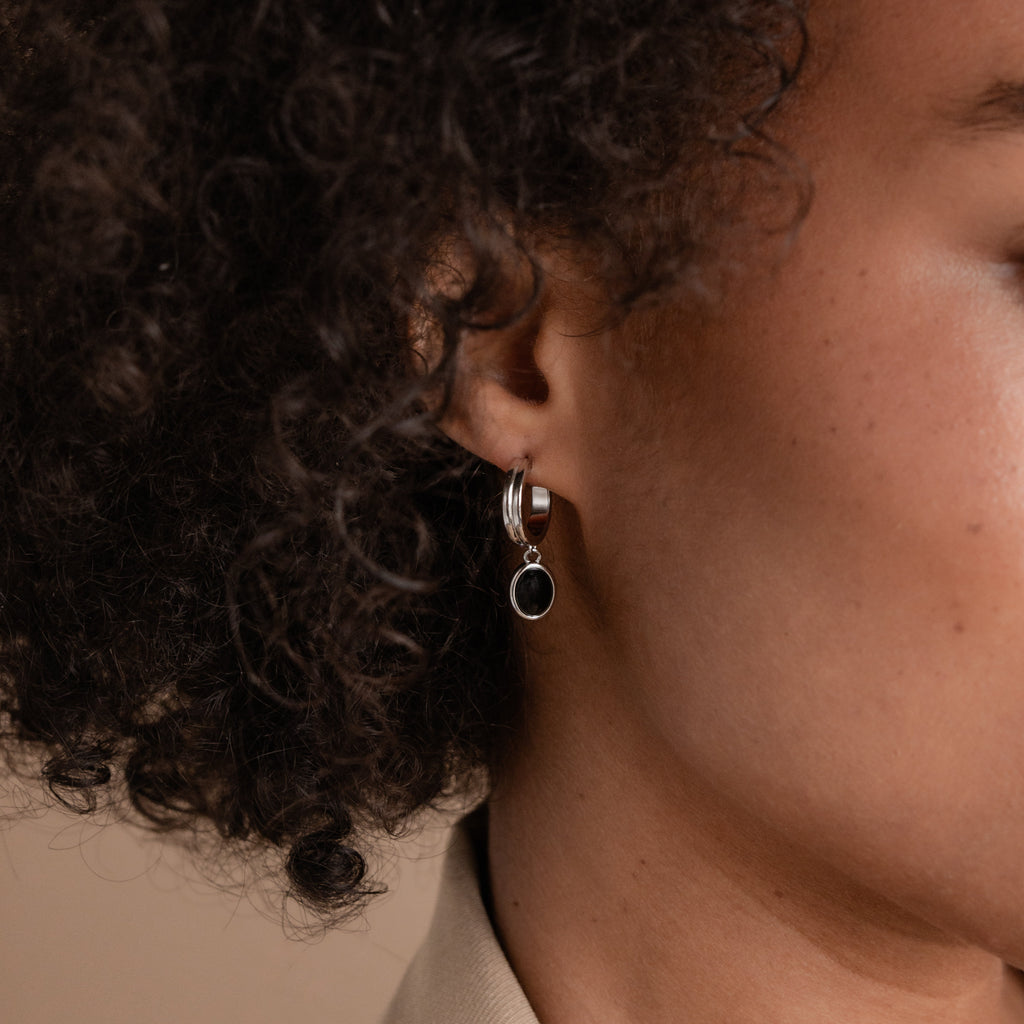 A close-up of a woman's ear adorned with elegant Black Gemstone Drop Hoops.