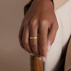 Model’s hand resting on chair arm, wearing a gold filigree ring with vintage swirl.