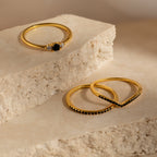 Three Black Curve Ring Sets featuring elegant black stones are displayed on beige stone blocks in soft natural light.