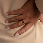 A hand with manicured nails wears the stylish Black Curve Ring Set, resting on a beige fabric background.