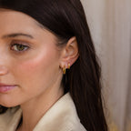 A woman with brown hair, wearing the Mini Hammered Hoops Set and a beige top, faces left against a soft background.