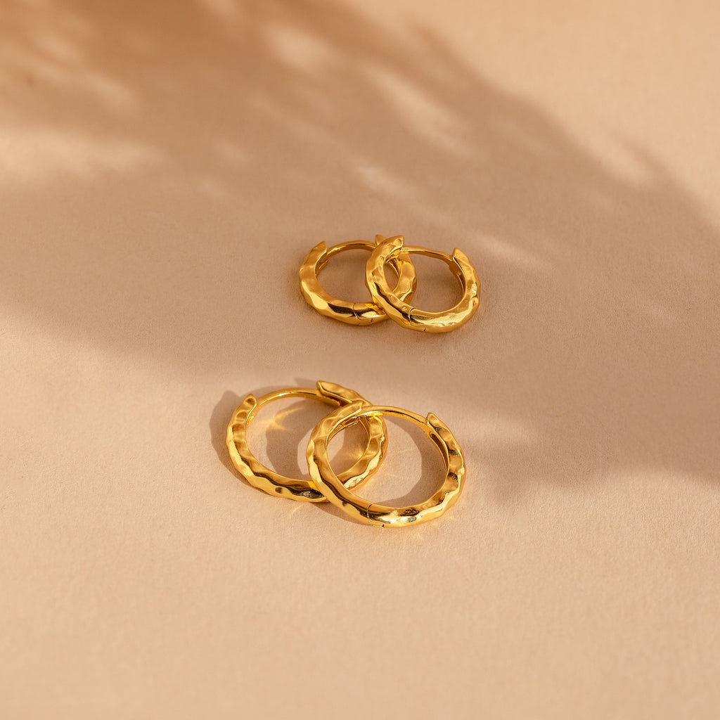 Two pairs of Mini Hammered Hoops Set in gold are displayed on a beige surface with soft shadows.