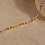 The Mini Name Birthstone Bracelet, featuring engraved name plates reading EVERLY, CLAIRE, and WHALEY, rests on a light marble surface—a perfect customizable gift for someone special.