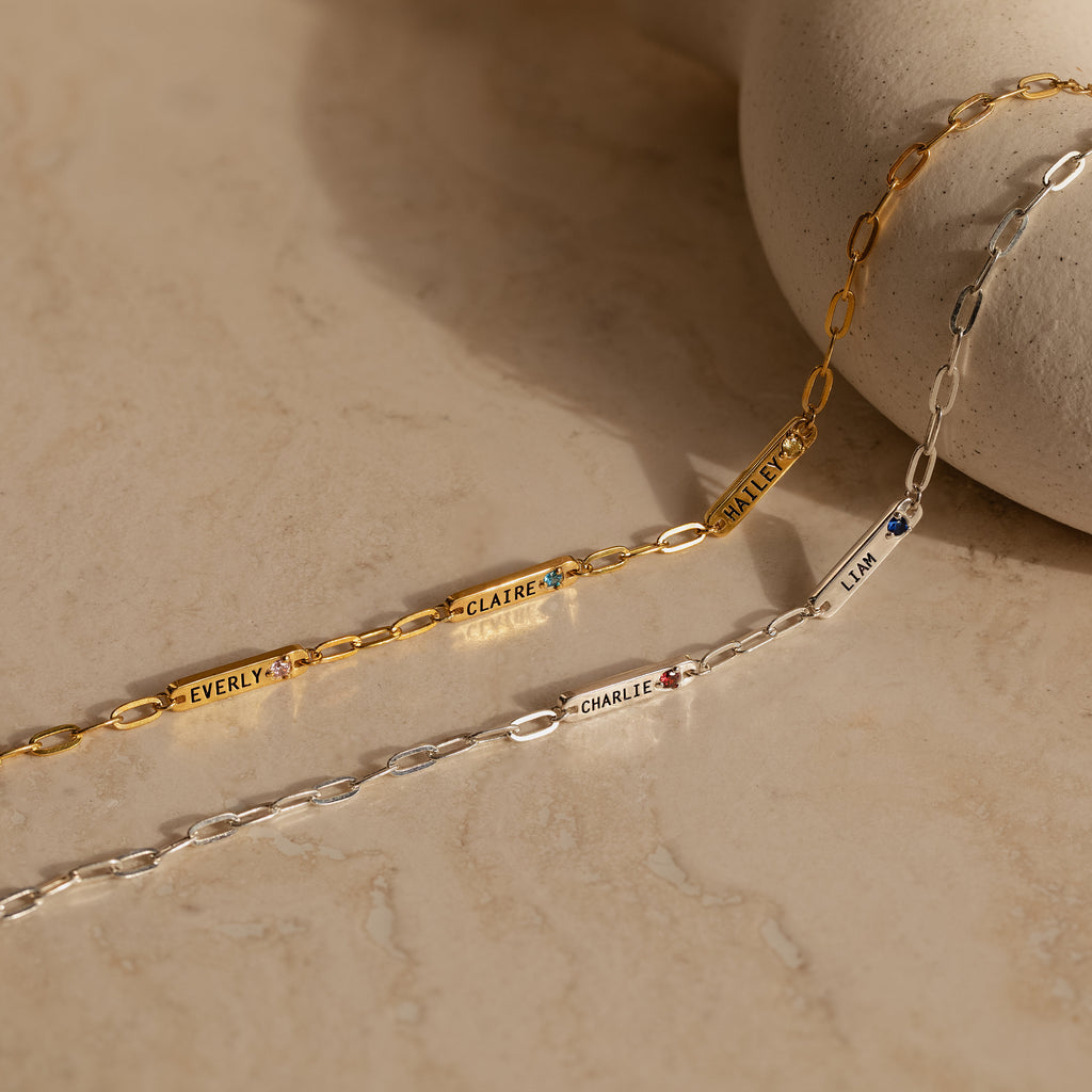 The Mini Name Birthstone Bracelet features gold and silver paperclip links with personalized engraving, making it a perfect customized gift.