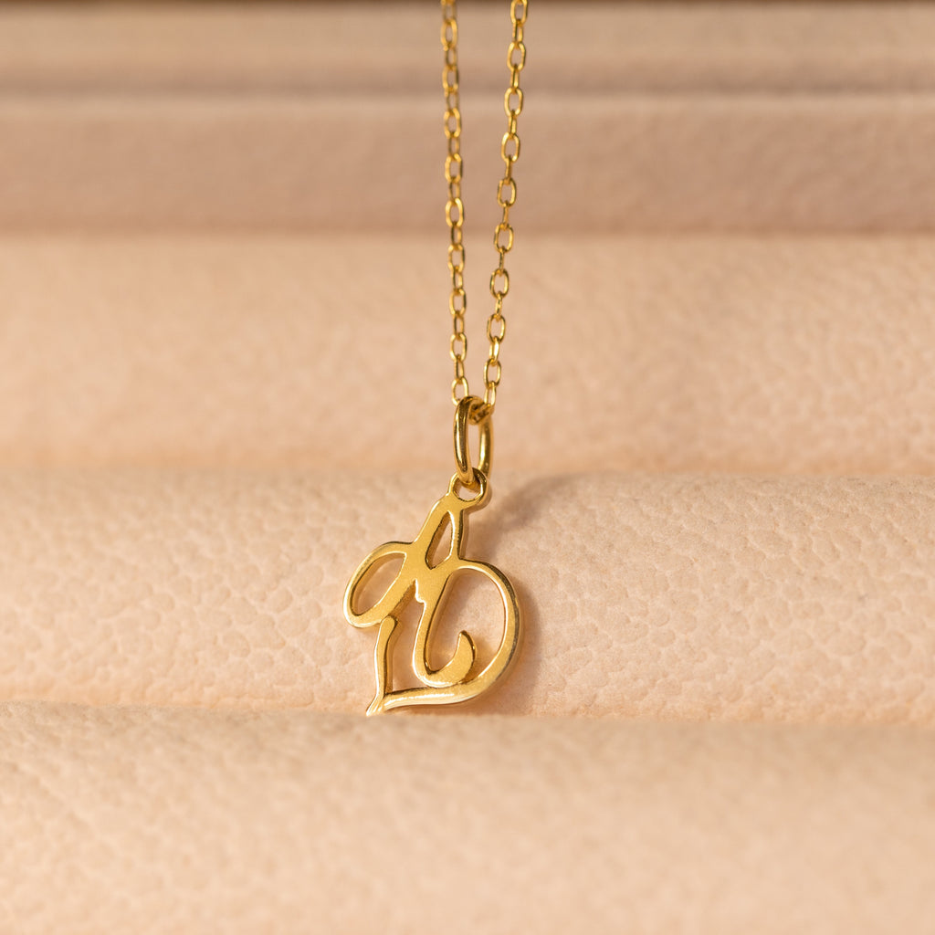 Initial Heart Necklace featuring a cursive letter b pendant on a soft beige textured surface—a beautiful custom piece and the perfect gift for someone you love.