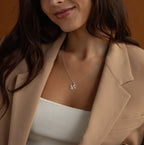 A woman in a beige blazer and white top smiles softly while wearing the Initial Heart Necklace, featuring a silver W pendant.