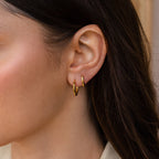 Close-up of a woman's ear with two Mini Hammered Hoops and long brown hair, highlighting the elegance of these gold or silver hoop earrings.