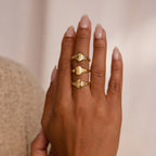 A hand wearing three Initial Birthstone Signet Rings on the middle finger, each with a unique engraved design—ideal for a personalized ring or custom gift.
