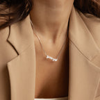 A woman wearing a beige blazer and a Retro Name Necklace in Box Chain with a silver Scorpio pendant.