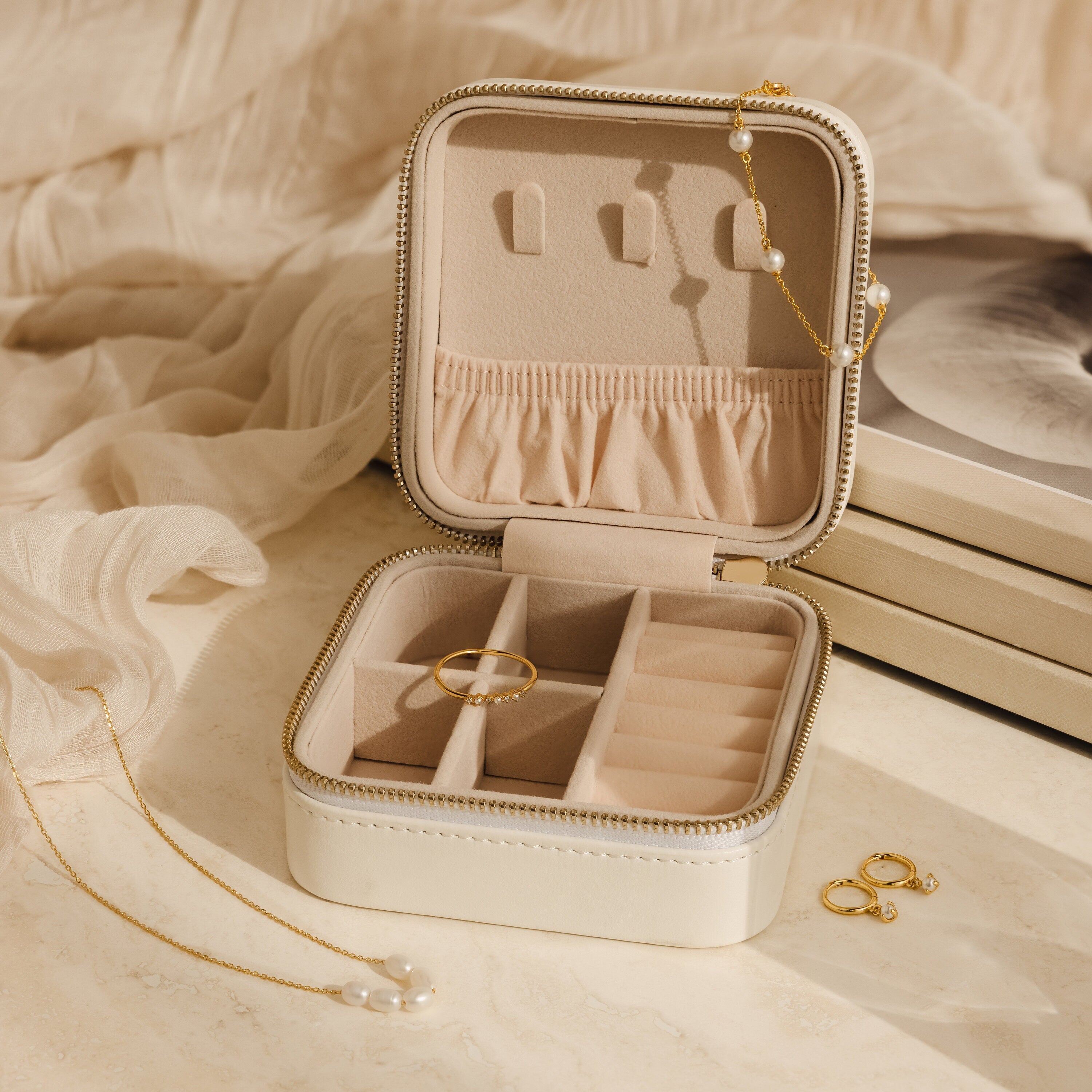 The Mystery Jewelry Box displays handpicked rings, a pearl necklace, and gold earrings on a beige fabric background.