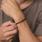 Wearing a taupe shirt, he puts on the Men's Black Cuff Bracelet—a stylish accessory and perfect gift for him.