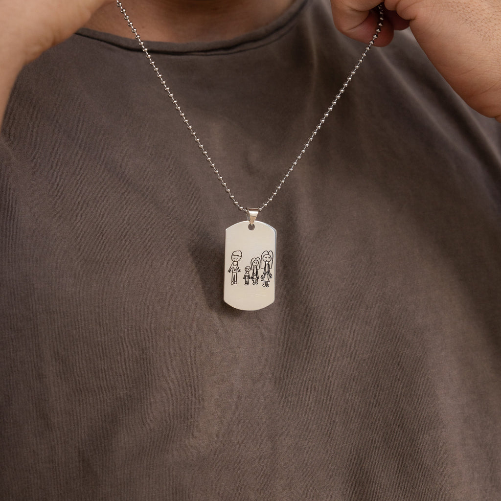 A person holds the Men's Dog Tag Necklace, personalized with a pendant engraved with stick-figure drawings of four people—a thoughtful Father's Day gift.