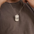 A person holds the Men's Dog Tag Necklace, personalized with a pendant engraved with stick-figure drawings of four people—a thoughtful Father's Day gift.